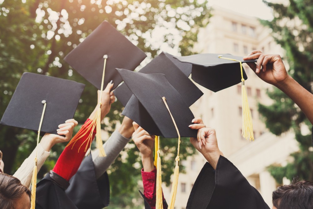 A group of students celebrating their graduation by throwing caps in the air closeup
