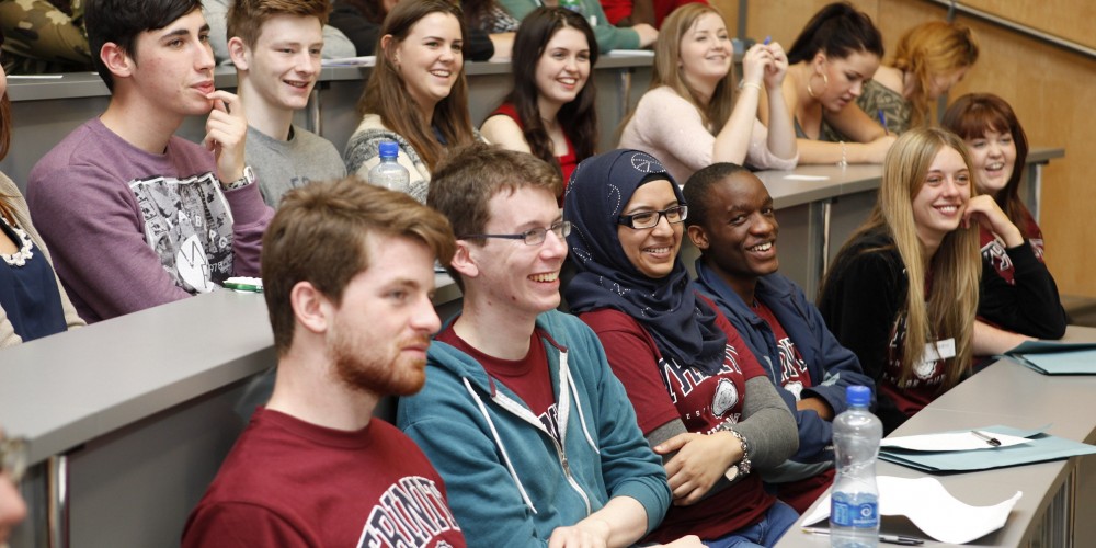 A group of students in a lecture hall laughing and smiling