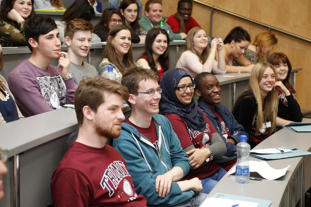 A group of students in a lecture hall laughing and smiling