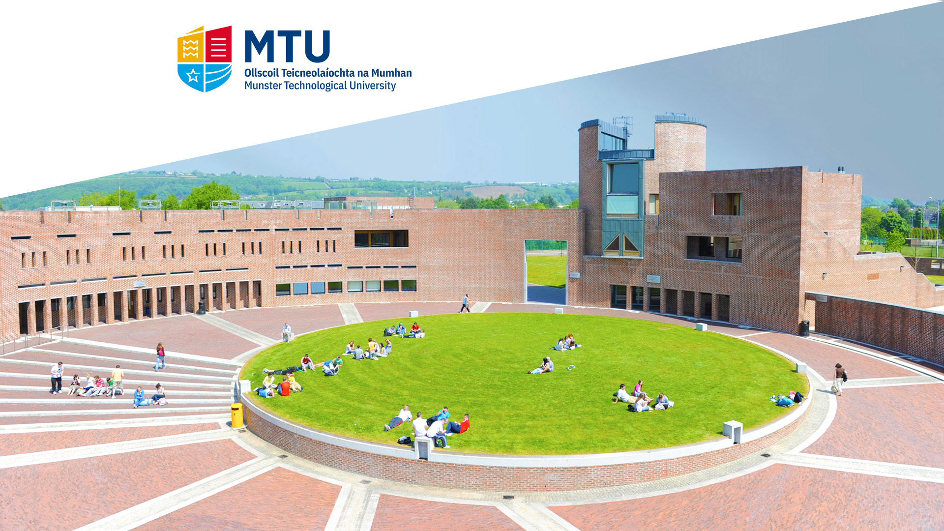 Munster Technological University campus with a circular grass area with students sitting around on the grass.