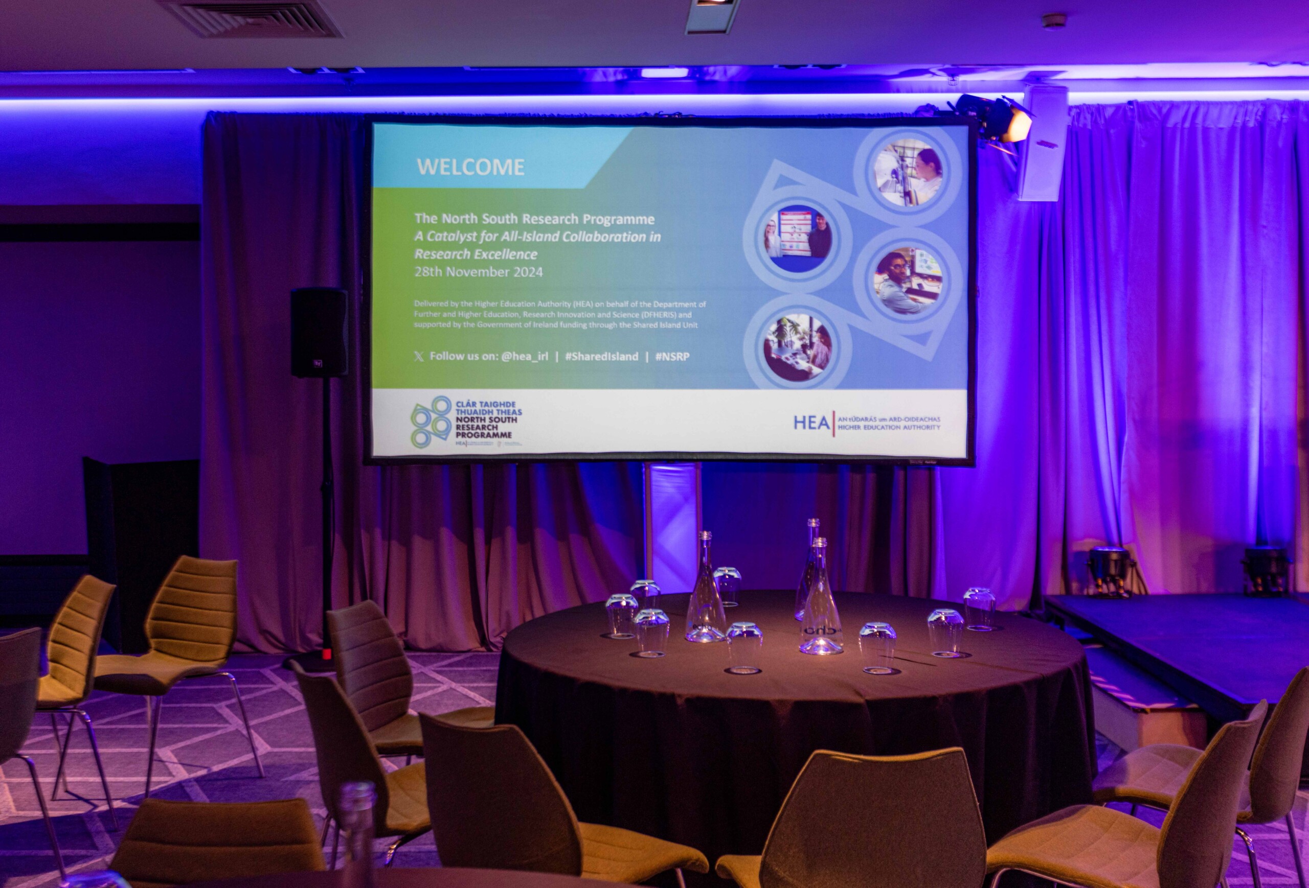 Photo of a table and a screen with the day's itinerary at the North South Research Conference 2024.