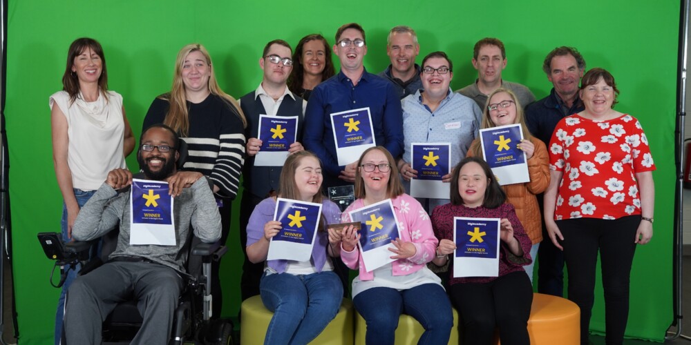 Group of people in front of greenscreen holding certificates