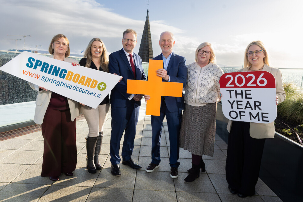 Group of six people posing holding handheld signs promoting Springboard+ 2026