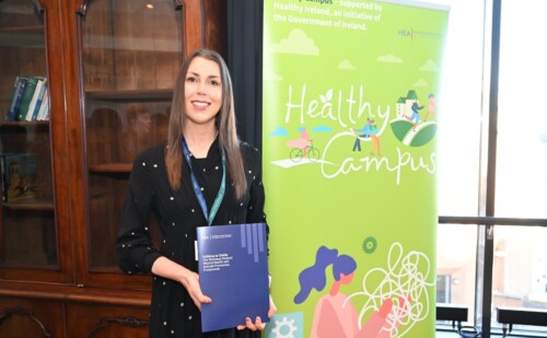 Lady holding the new framework, to the right a HEA Healthy Campus pull stand in green